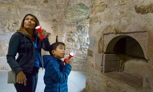 Woman and child exploring Craigmillar Castle and using torches