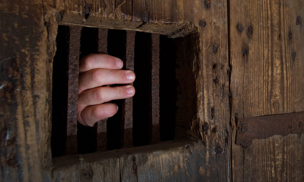 Detail of the door of a prison cell in the Argyle Tower with a hand holding a bar
