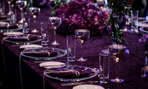 View of the Queen Anne Room set up for a private event, long table has a purple them with silver goblets