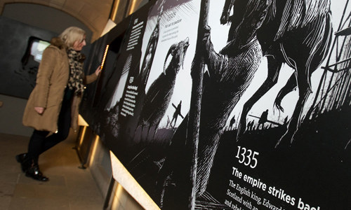 Interior view of the Fight for the Castle exhibition with a woman reading information boards