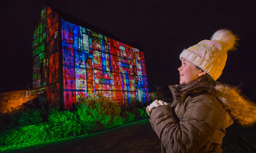 Photo shoot for Castle of Light with girl looking at the light projection on St Margaret's Chapel