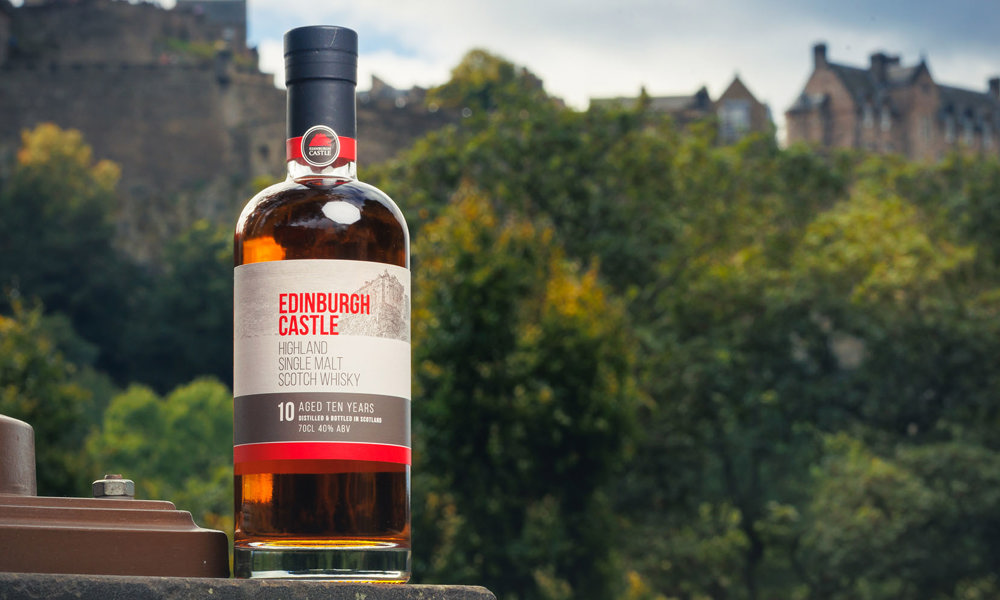 A bottle of Edinburgh Castle Whisky with the castle in the background