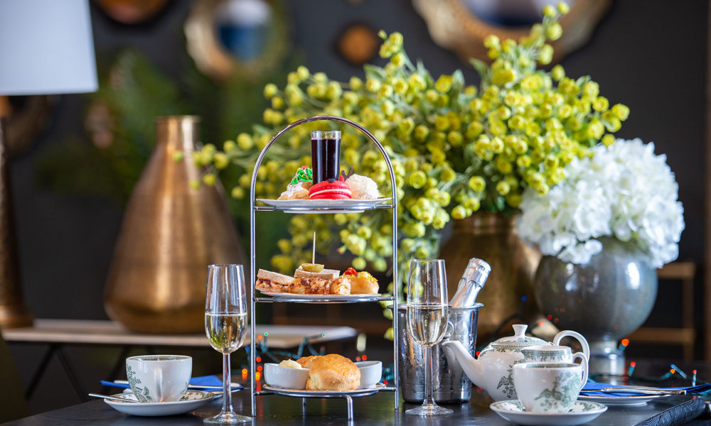 A selection of savoury and sweet treats on a cake stand along with tea and prosecco