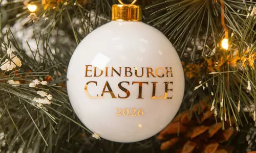 A round white Christmas tree bauble with 'Edinburgh Castle 2026' written in gold