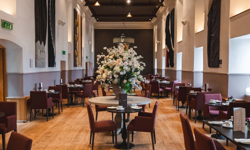 Tables set up for Afternoon Tea in the stunning Queen Anne Room with a beautiful large flower arrangement