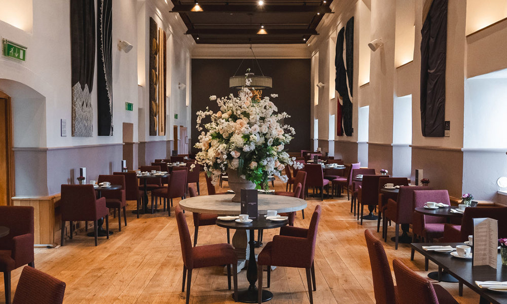 Tables set up for Afternoon Tea in the stunning Queen Anne Room with a beautiful large flower arrangement